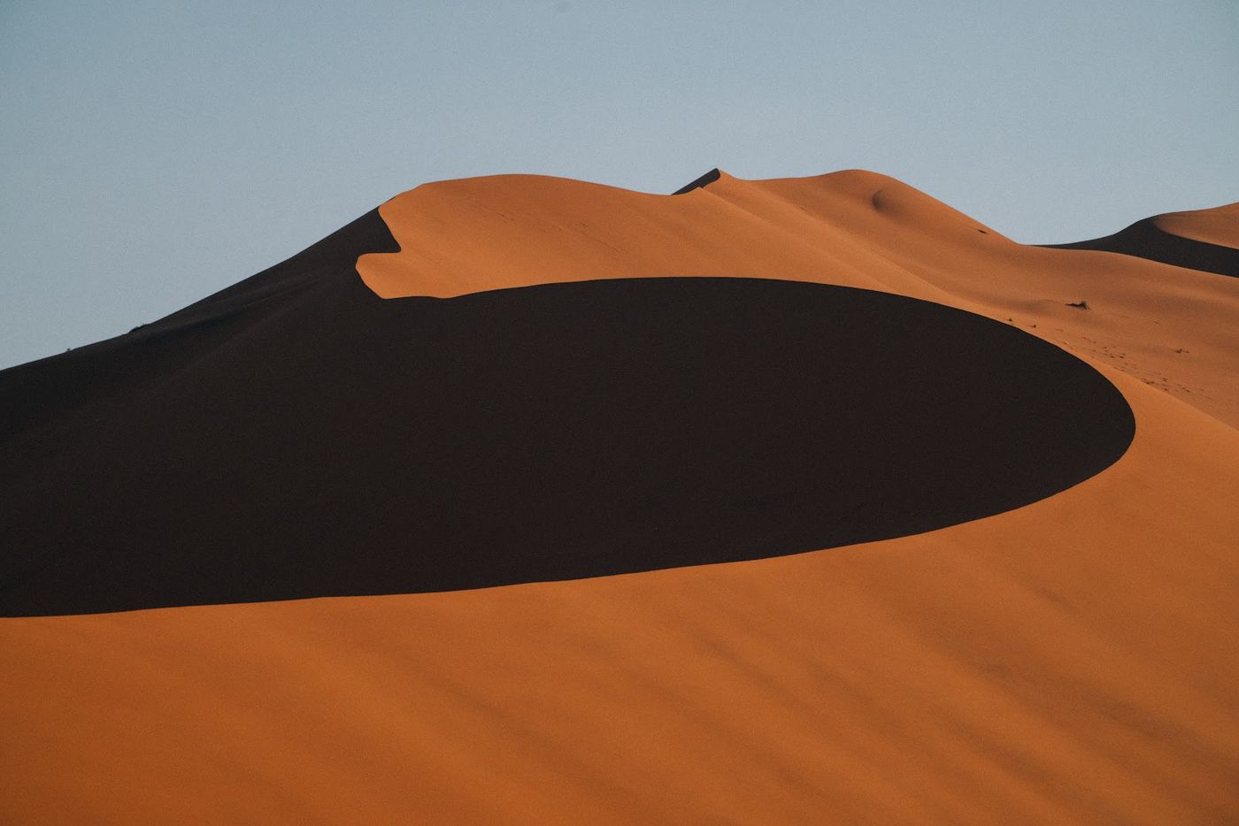 Sweeping shadow across the crest of a red Namib dune