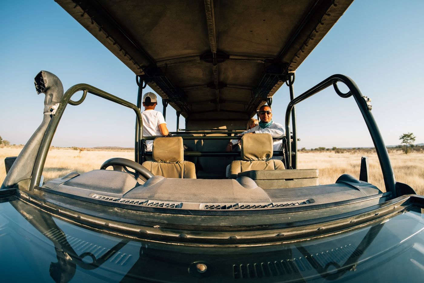 View from inside an open safari vehicle rolling through golden savanna